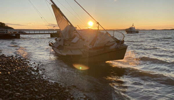 Strandad segelbåt ligger vid en sandstrand i solnedgången