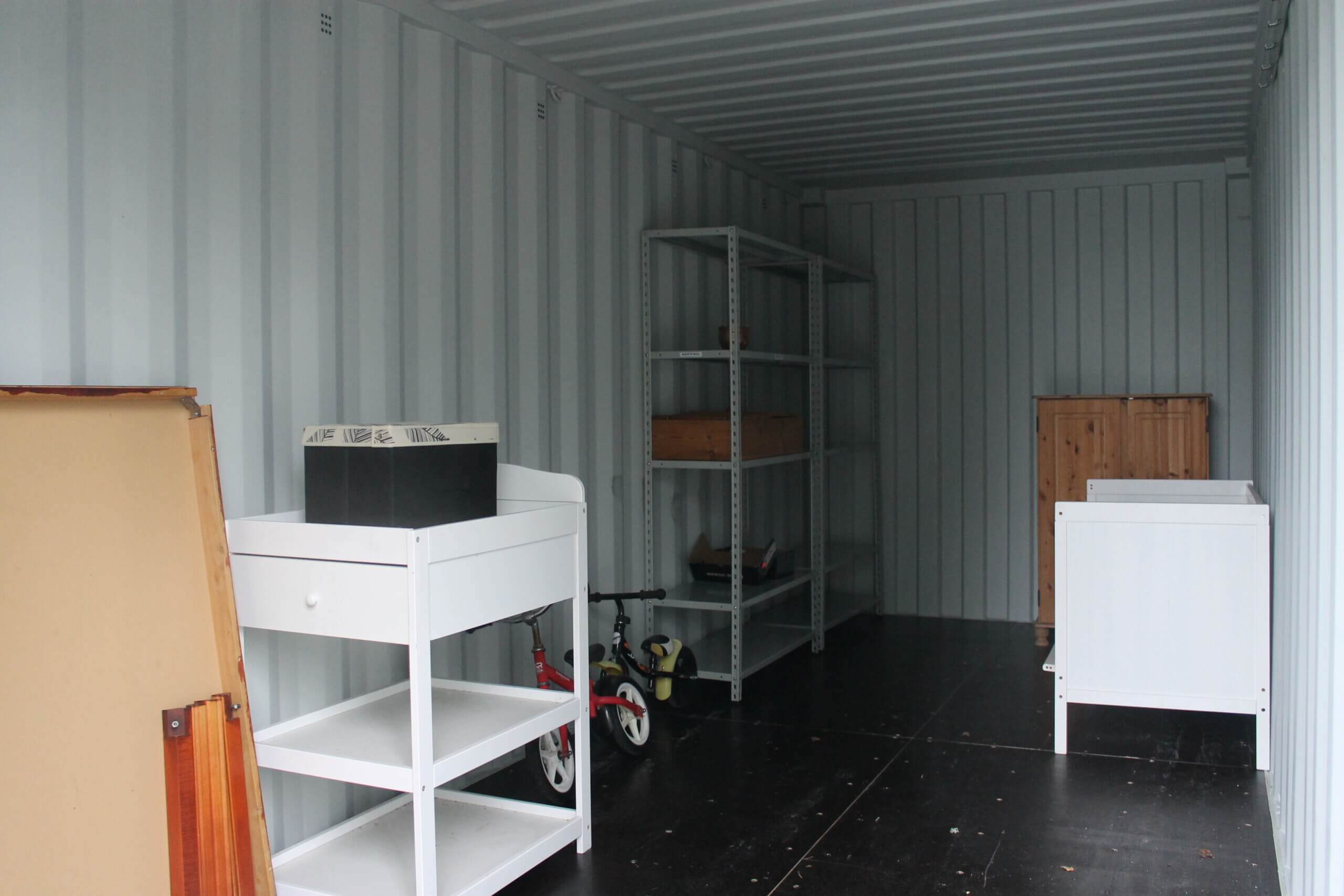 Bild inne i en container. I containern finns några möbler i trä. containern finns på Karis avfallsstation.