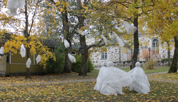 Halloweendekorationer utomhus, utanför Ekenäs kyrka. Spöken som dansar i ring och mindre spöken och fladdermöss hänger från träden.