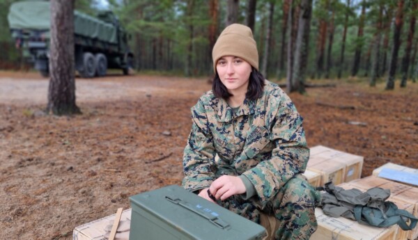 Ung kvinnlig soldat bland ammunitionslådor.