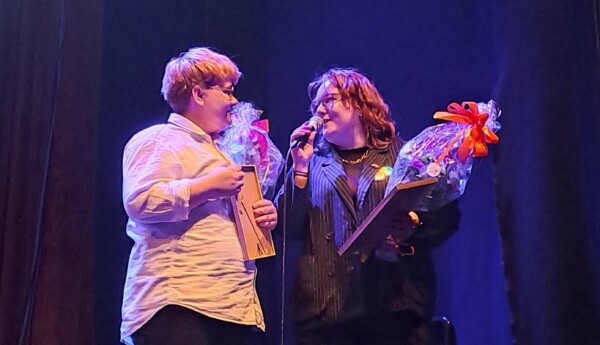 Två personer med blommor på en scen