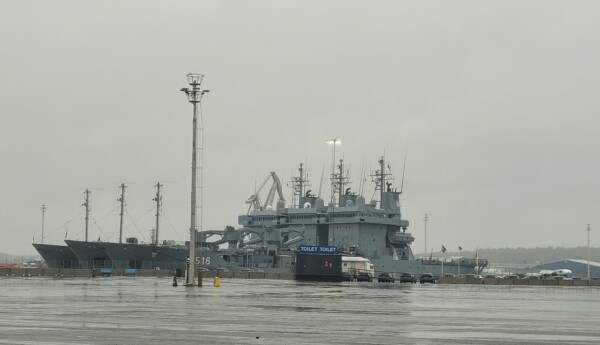 Ett grått militärfartyg förtöjt vid hamnen.