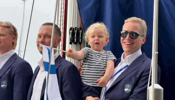Tre seglare i kavaj och en liten pojke med Finlands flagga