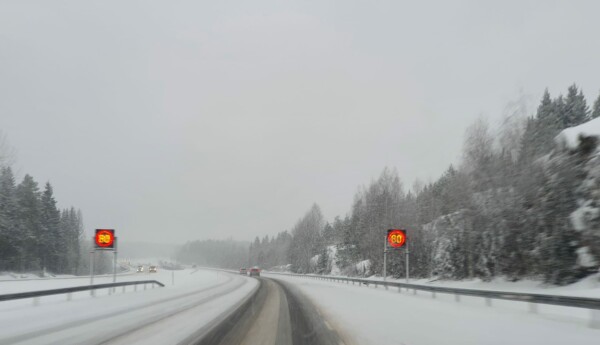 Snöyra på motorväg, hastighetsskyltar som visar 80 på bägge sidor om vägen