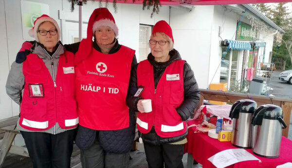 Tre kvinnor i Röda Kors-västar med tomteluvor