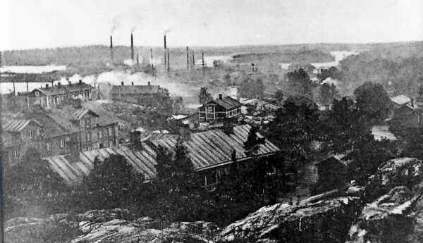svartvit bild över fabrikspipor och bostadshus