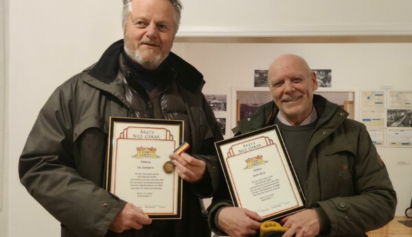 Två män med inramade diplom och en medalj