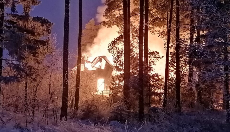 Brinnande hus i ett skogsbryn