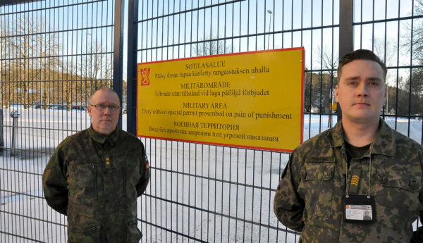 Två militärer står framför ett stängsel