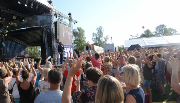 musikfestival med många händer uppsträckta mot mannen på scenen