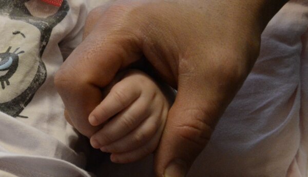 Vuxen hand håller i en babyhand