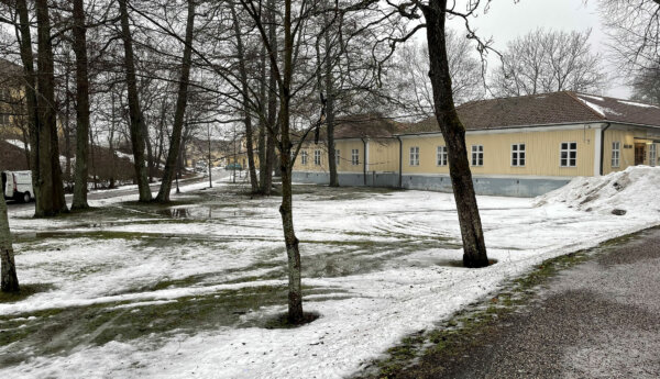 parkliknande område med snö och ett gult lågt trähus