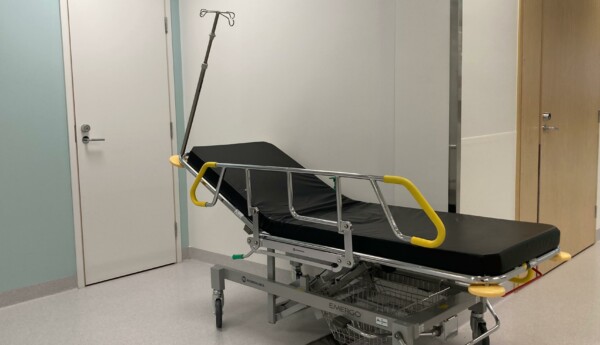Sjukhusbrits med svart madrass står i en korridor