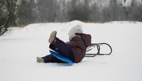 Ett barn i snö med kälke och "peffis"
