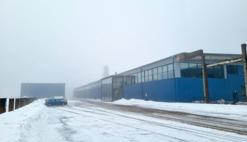Blå fabriksbyggnad i dimma.