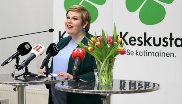politikerkvinna bakom bord med tulpaner och mikronfoner