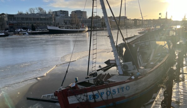 stor träbåt som har sjunkit i en å med is