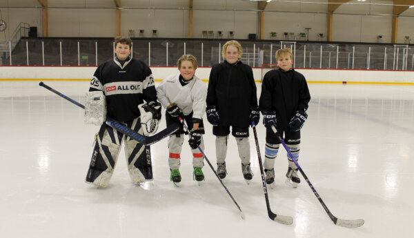 Fyra unga killar står bredvid varandra på isen i Karis ishall. pojkarna är klädda i ishockeyutrustning. De spelar i Ice Team Raseborgs U13 lag.