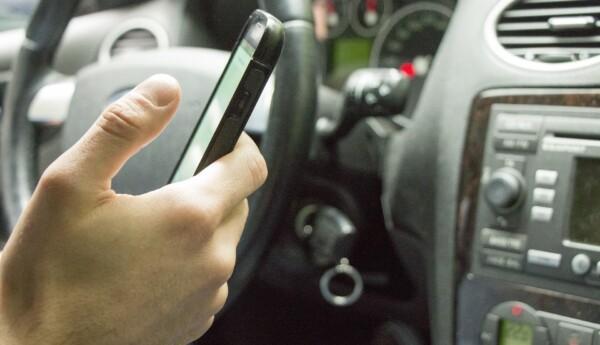Hand som håller i smarttelefon inne i en personbil