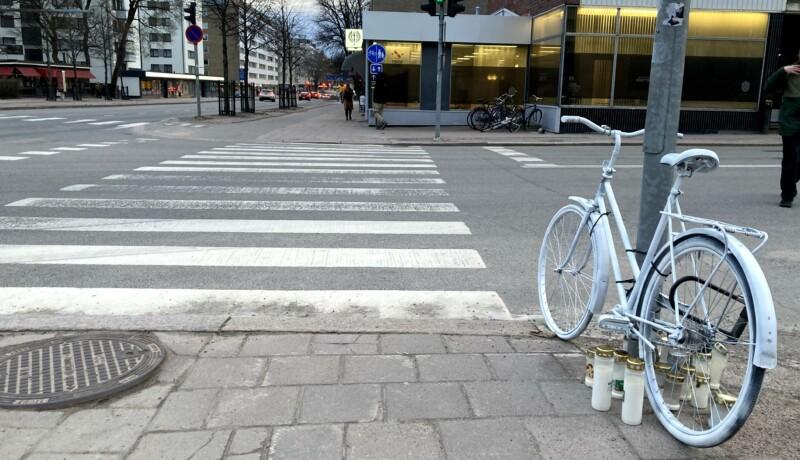 Vitmålad cykel och gravljus på trottoar