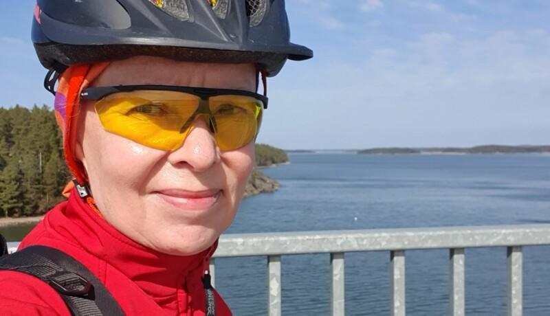 Kvinna i cykelhjälm och cykelglasögon på en hög bro.