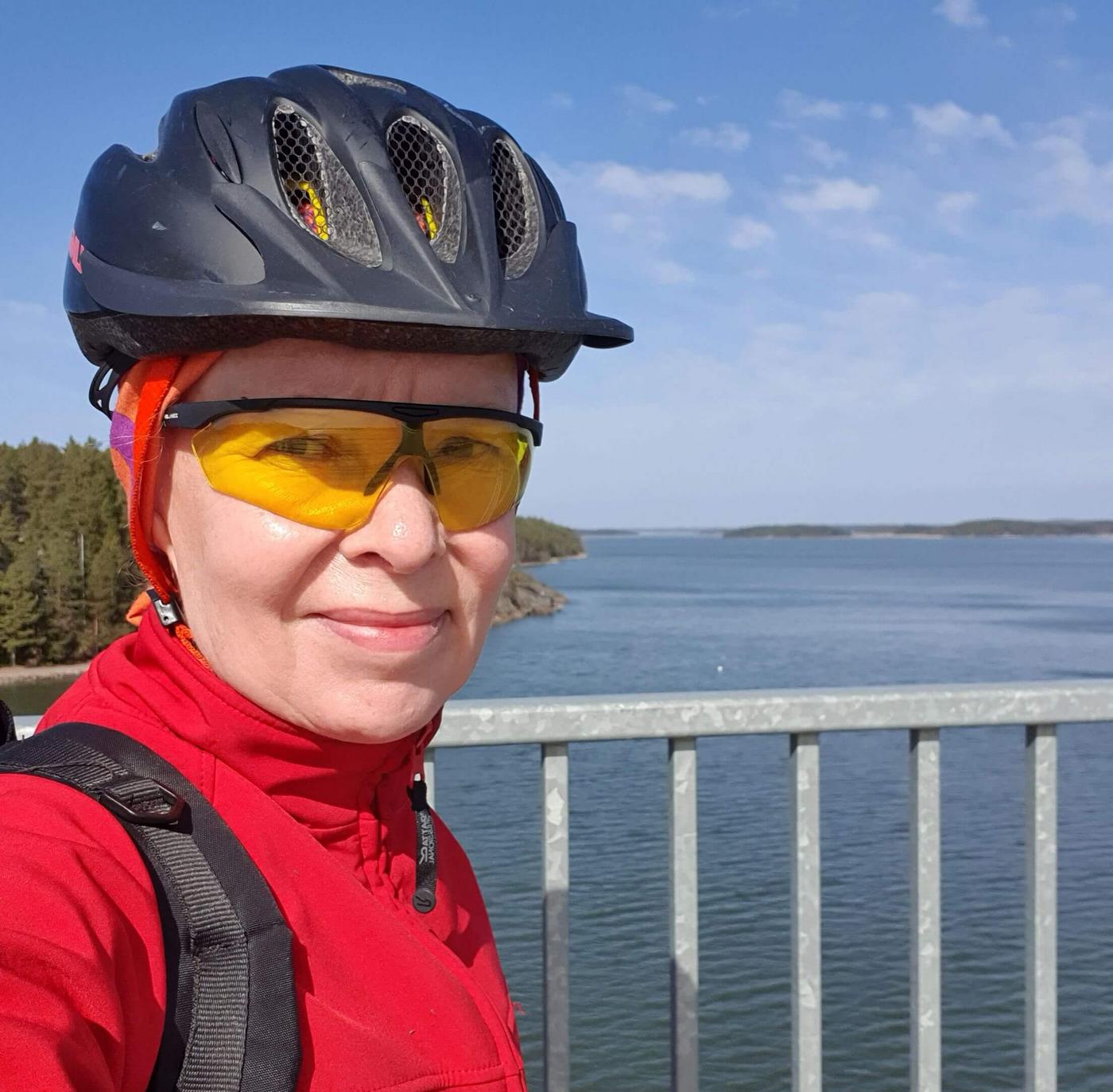 Kvinna i cykelhjälm och cykelglasögon på en hög bro.