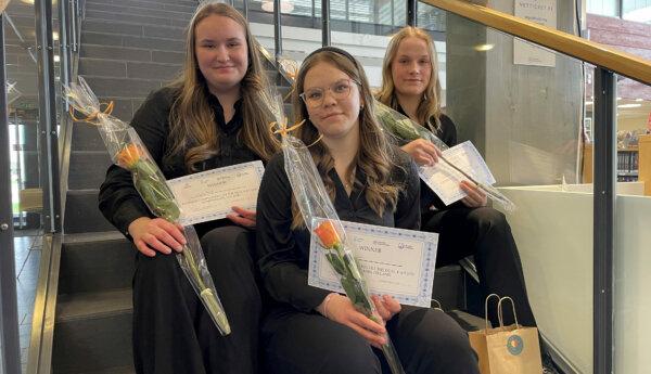 Tre flickor med blommor ch diplom i en trappa