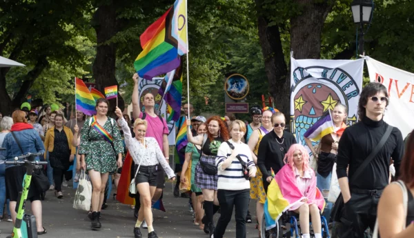 En parad av människor som viftar med flaggor och plakat i regnbågens färger