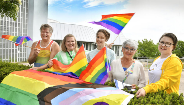 Fyra leende personer med regnbågsflaggor