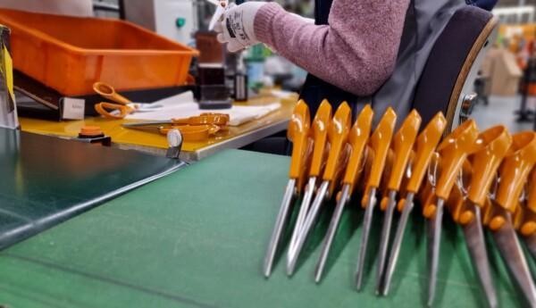 Kvinna testar nytillverkade saxar med orange handtag.