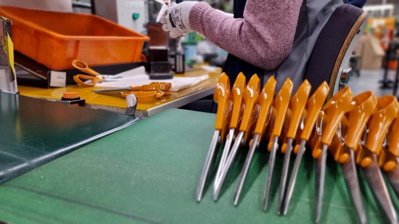 Kvinna testar nytillverkade saxar med orange handtag.
