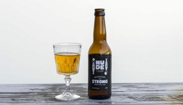 Ett glas på fot med öl i och en brun glasflaska med svart etikett