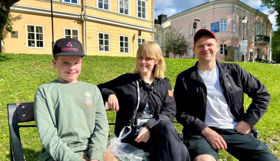 Unto Turunen, Niina Turunen och Oskari Turunen sitter på en bänk vid Aura å.