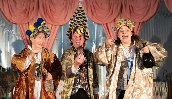Tre skådespelare på en scen iklädda lustiga peruker gjorda av korkar, ölburkar och toalettpappersrullar.
