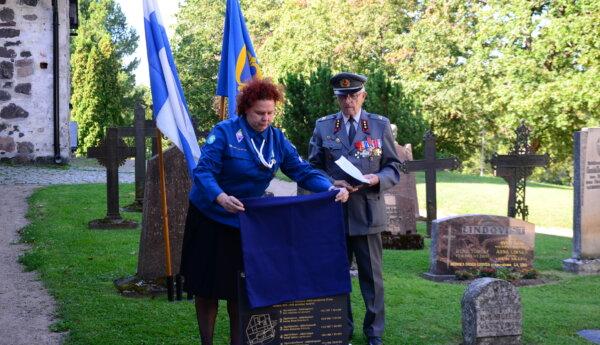 en kvinna i scoutuniform och en man i militäruniform på en gravgård