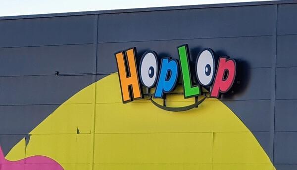 Färggrann skylt med texten "Hoplop" på byggnadsfasad.