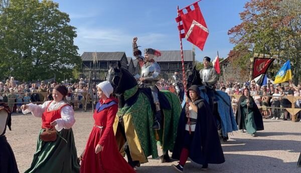 Hästar och riddare i en ingångsparad på en arena